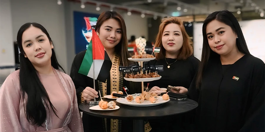 STARTRADER female team members serving UAE National Day sweets